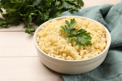 Photo of Delicious bulgur with parsley in bowl on wooden table, closeup. Space for text