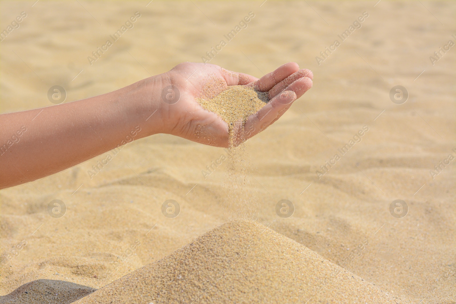 Photo of Child pouring sand from hand on beach, closeup with space for text. Fleeting time concept