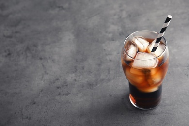 Photo of Glass of refreshing cola with ice on grey background. Space for text
