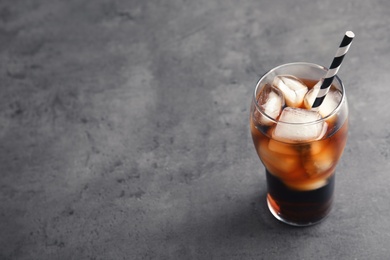 Glass of refreshing cola with ice on grey background. Space for text