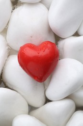 Photo of Red decorative heart on stones and water, top view