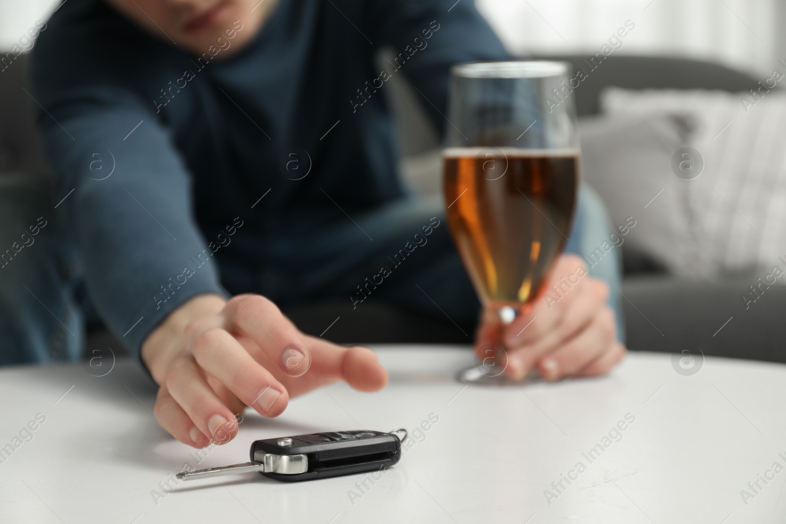 Photo of Drunk man reaching for car keys indoors, closeup. Don't drink and drive concept