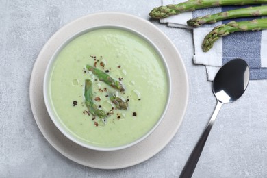 Photo of Delicious asparagus soup served on light grey table, flat lay