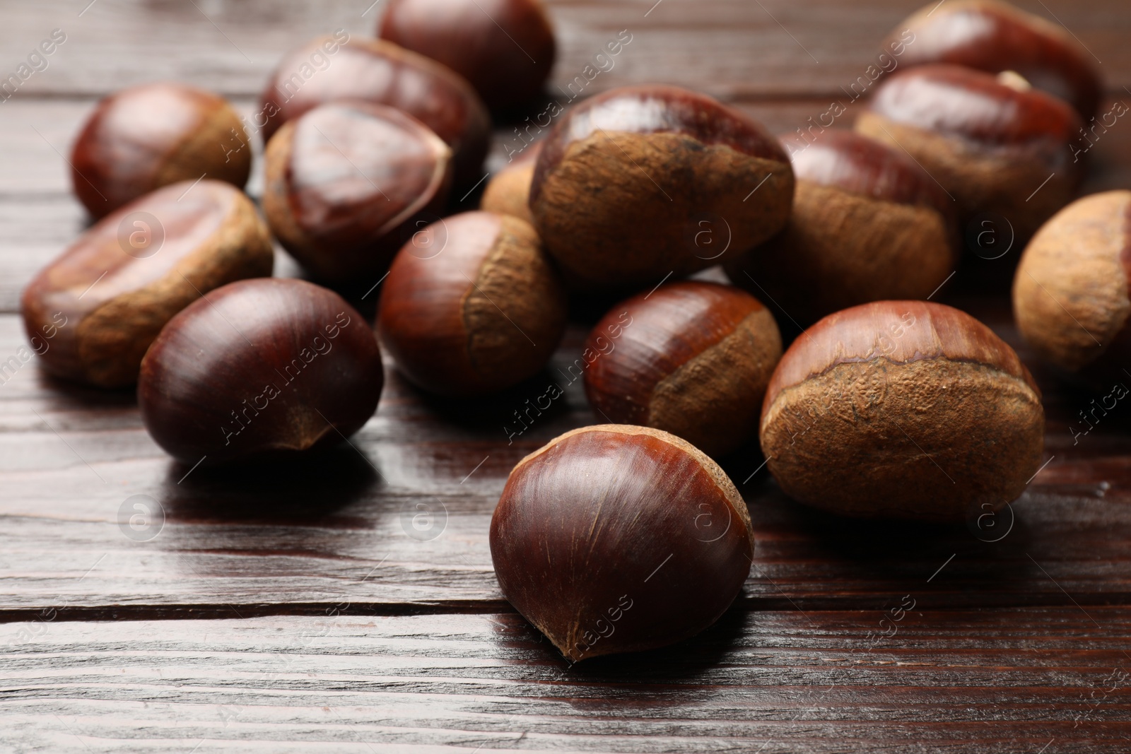 Photo of Sweet fresh edible chestnuts on wooden table, closeup