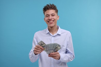 Photo of Happy man with dollar banknotes on light blue background