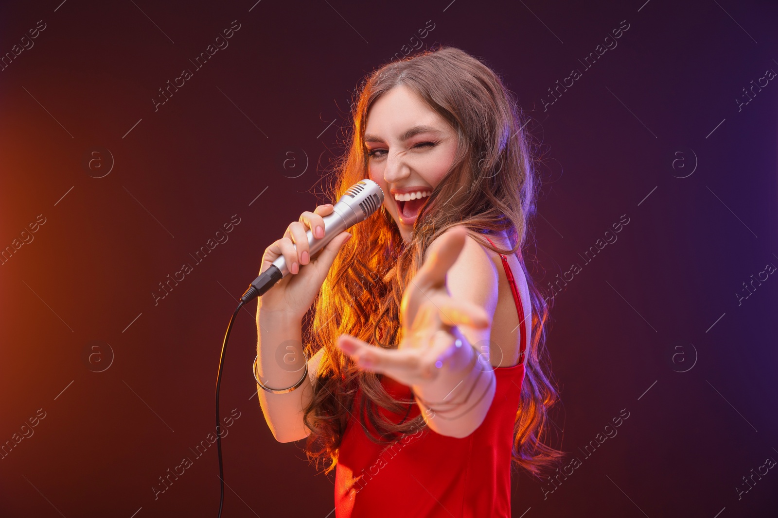 Photo of Emotional woman with microphone singing in color lights