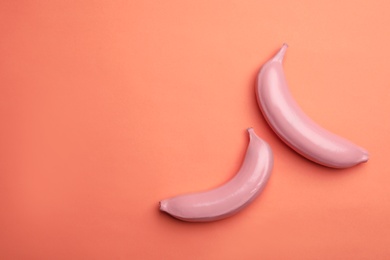 Photo of Flat lay composition with painted bananas and space for text on coral background