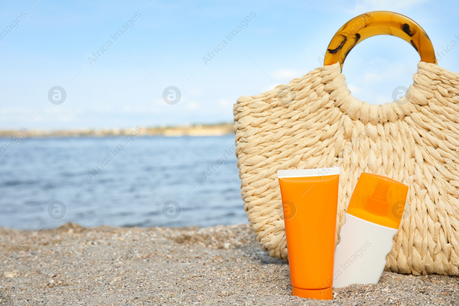 Photo of Composition with bottles of sun protection body cream on beach, space for text