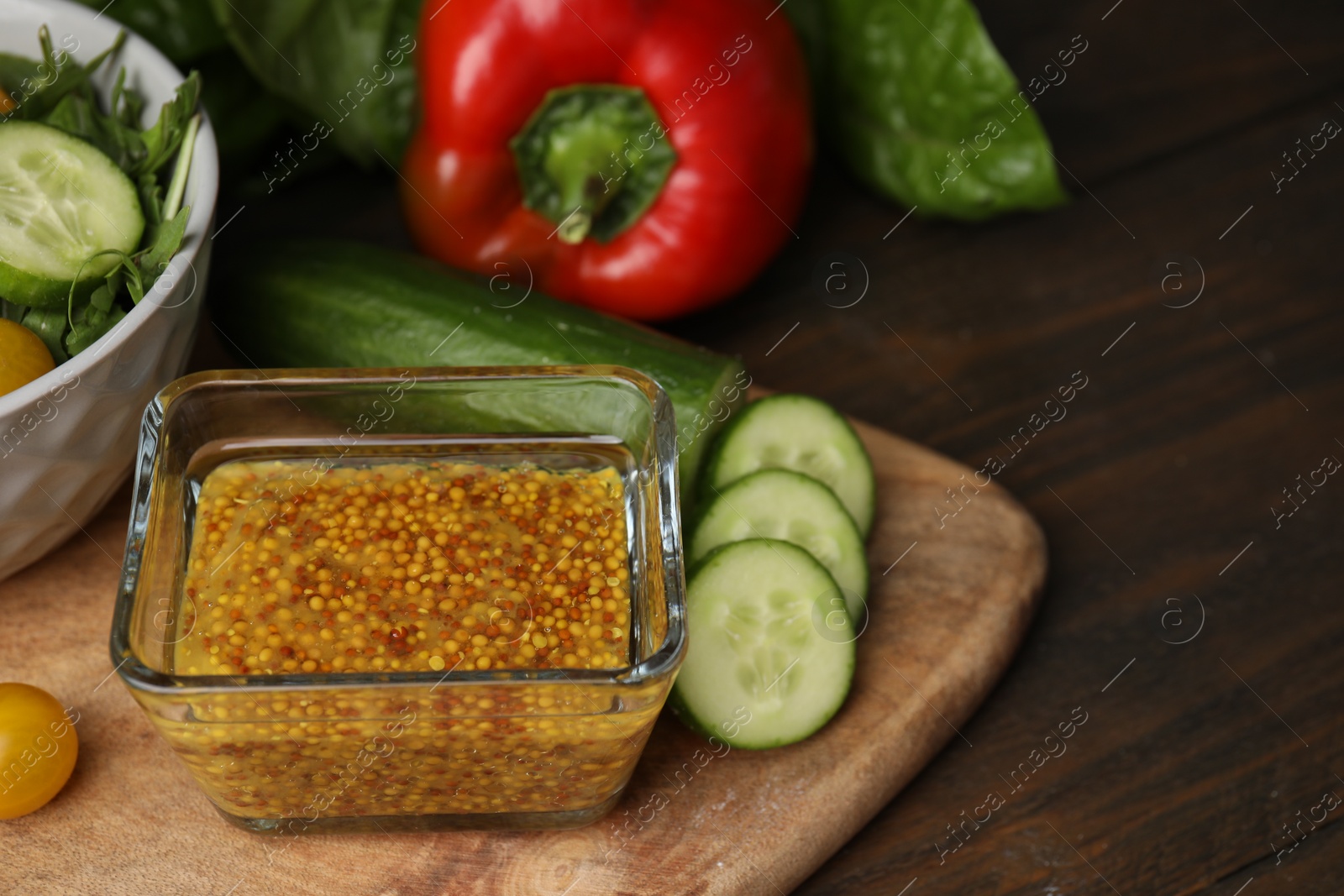 Photo of Tasty vinegar based sauce (Vinaigrette) in bowl and products on wooden table, closeup. Space for text