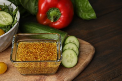 Photo of Tasty vinegar based sauce (Vinaigrette) in bowl and products on wooden table, closeup. Space for text