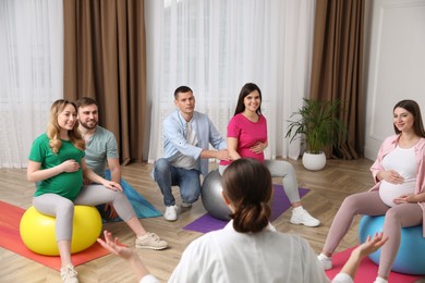 Photo of Pregnant women with men and doctor at courses for expectant parents indoors