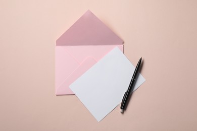 Blank sheet of paper, letter envelope and pen on beige background, top view. Space for text