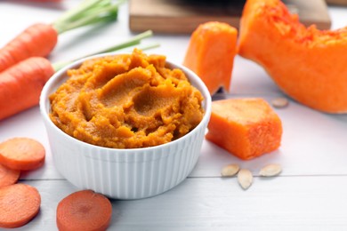 Photo of Bowl with tasty puree, carrots and pumpkin on white wooden table, closeup