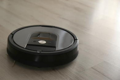 Modern robotic vacuum cleaner on wooden floor