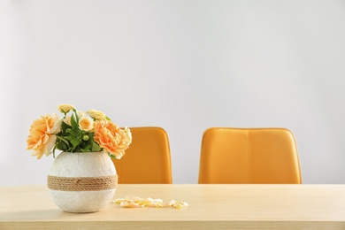 Vase with blooming flowers on table indoors