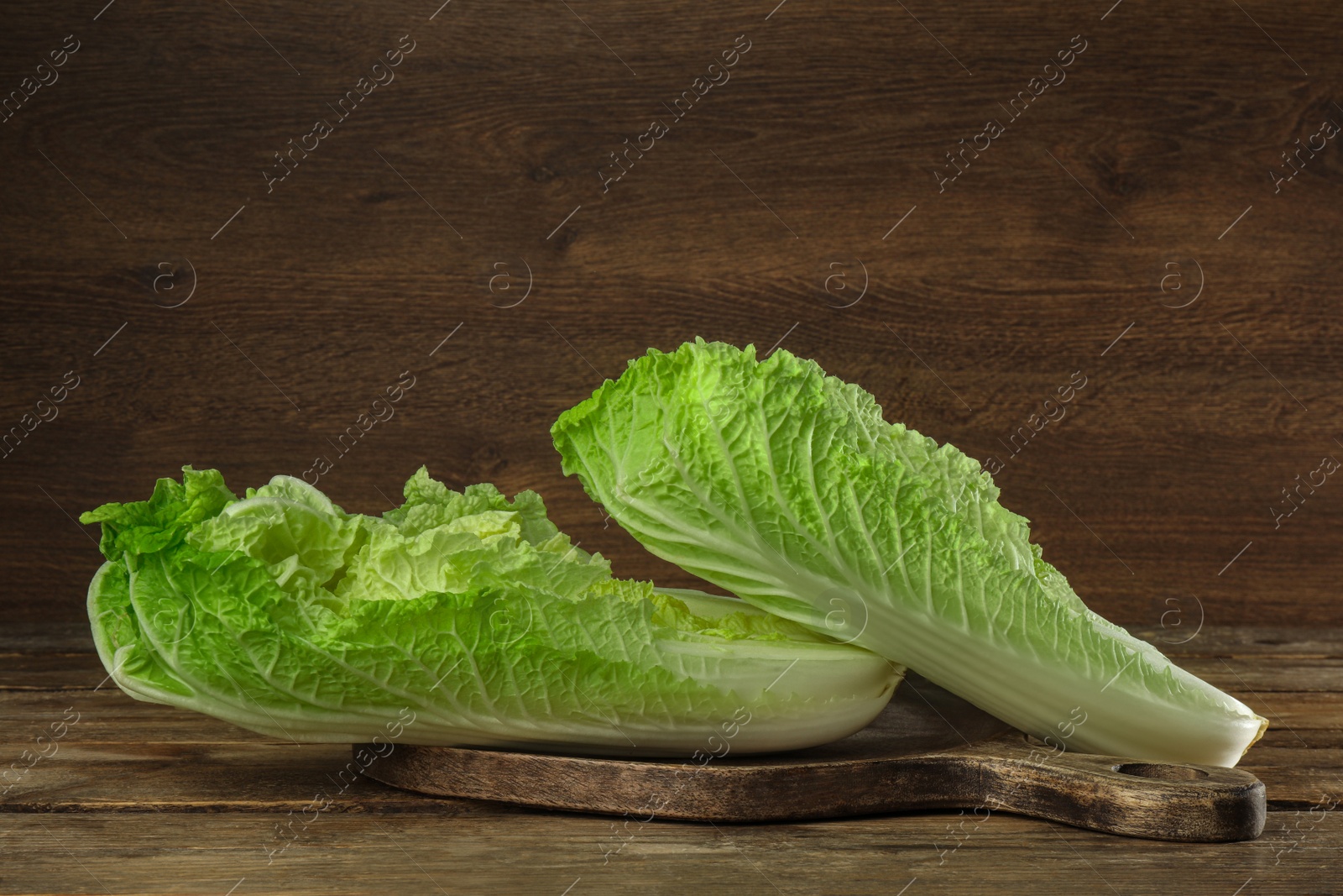 Photo of Cut fresh ripe Chinese cabbage on table against wooden background