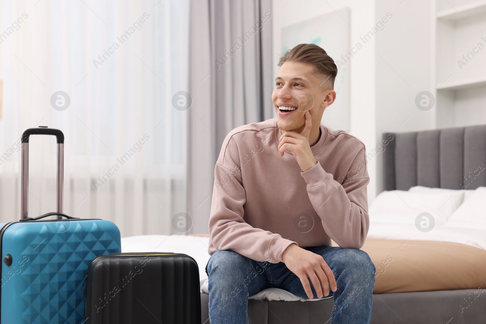 Photo of Smiling guest relaxing on bed in stylish hotel room