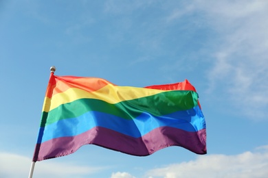 Photo of Bright rainbow gay flag fluttering against blue sky. LGBT community