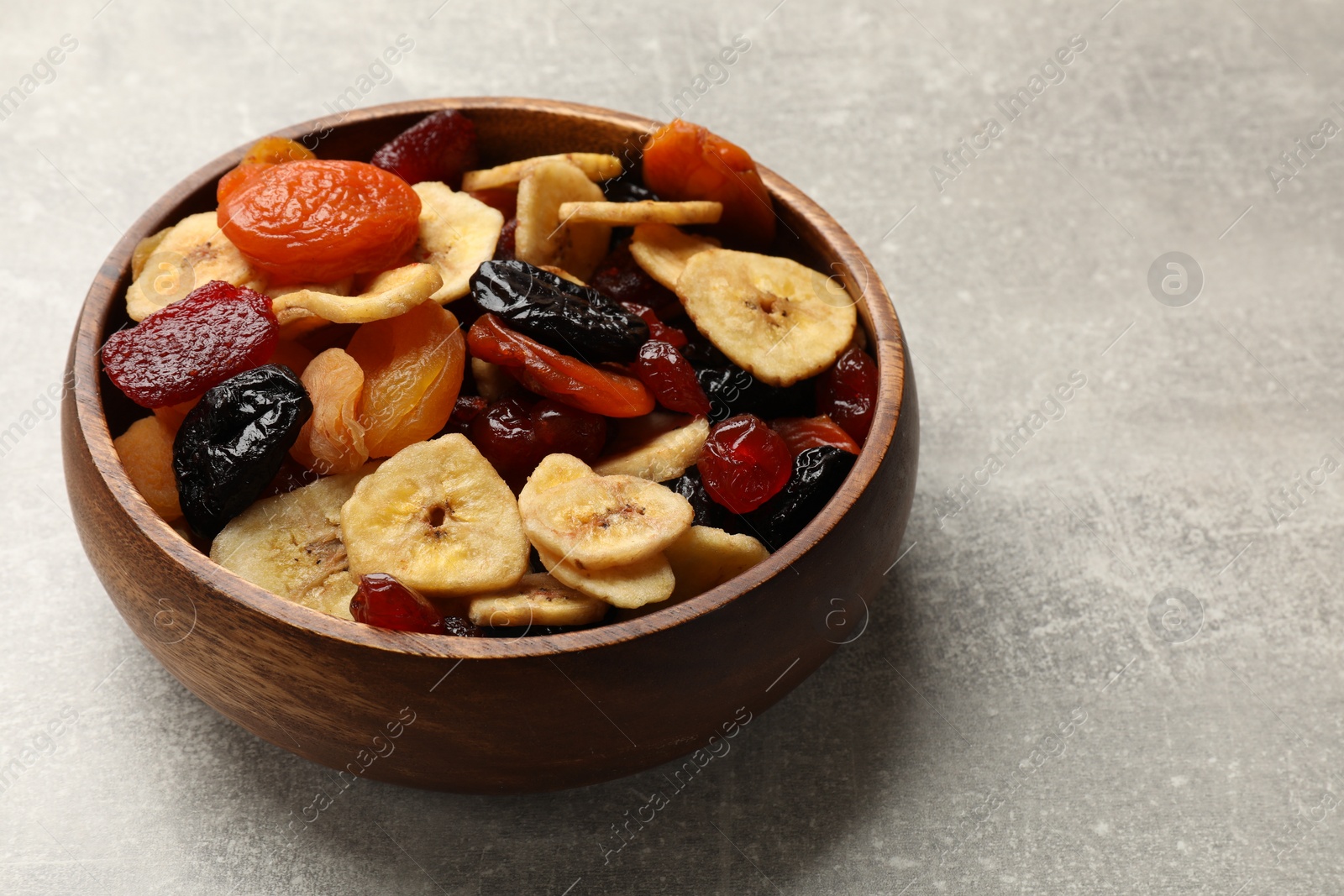 Photo of Mix of delicious dried fruits on grey table, closeup. Space for text