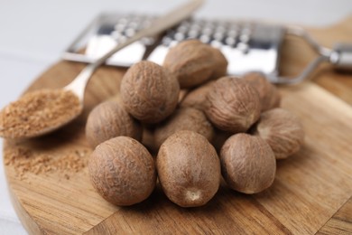 Heap of nutmegs on wooden board, closeup