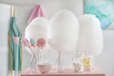 Photo of Tasty cotton candy and other sweets on table in room