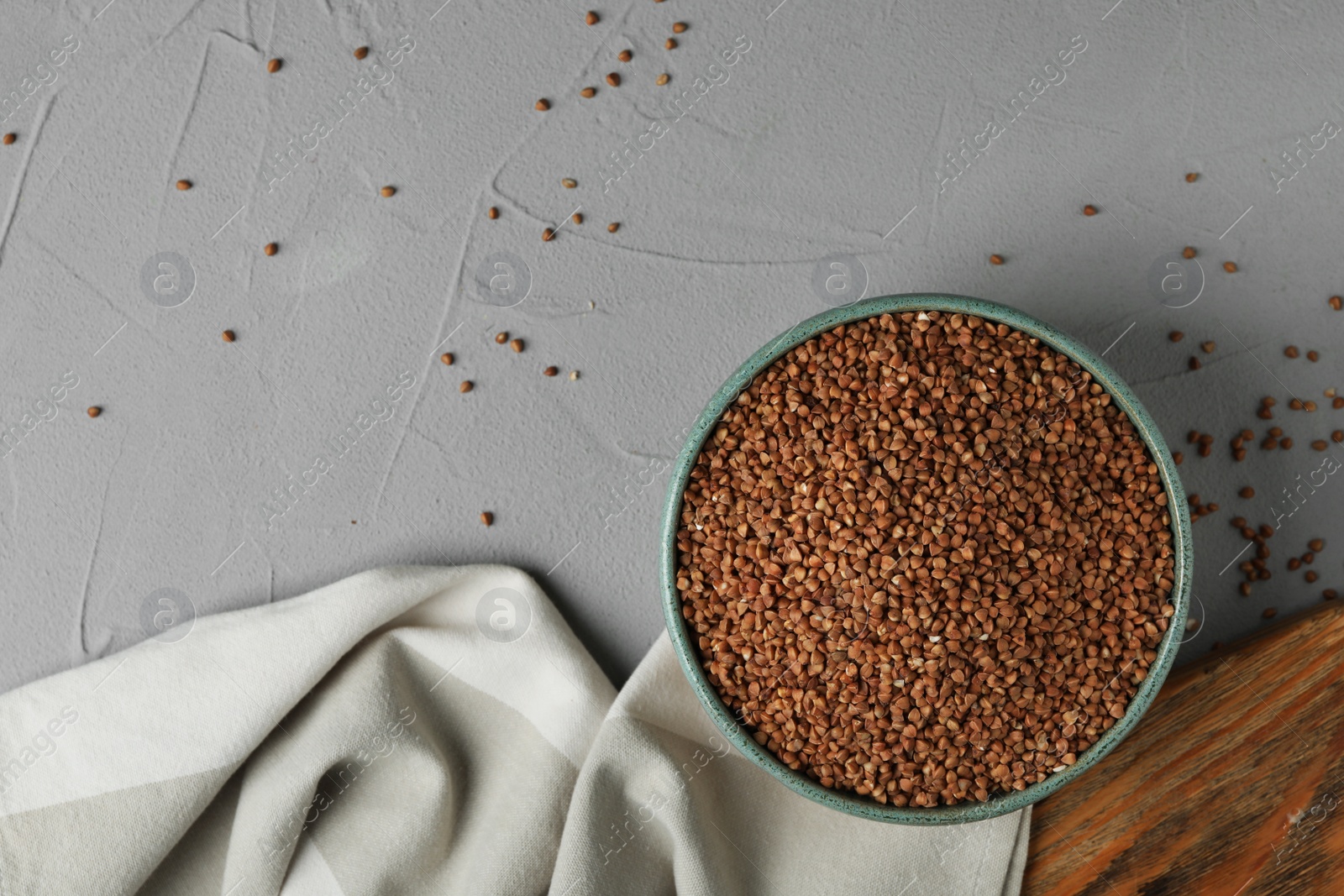 Photo of Uncooked buckwheat in bowl on table, flat lay. Space for text