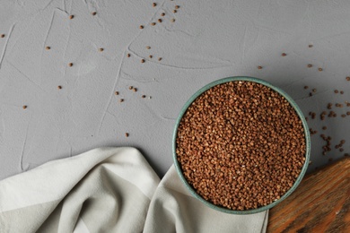 Uncooked buckwheat in bowl on table, flat lay. Space for text