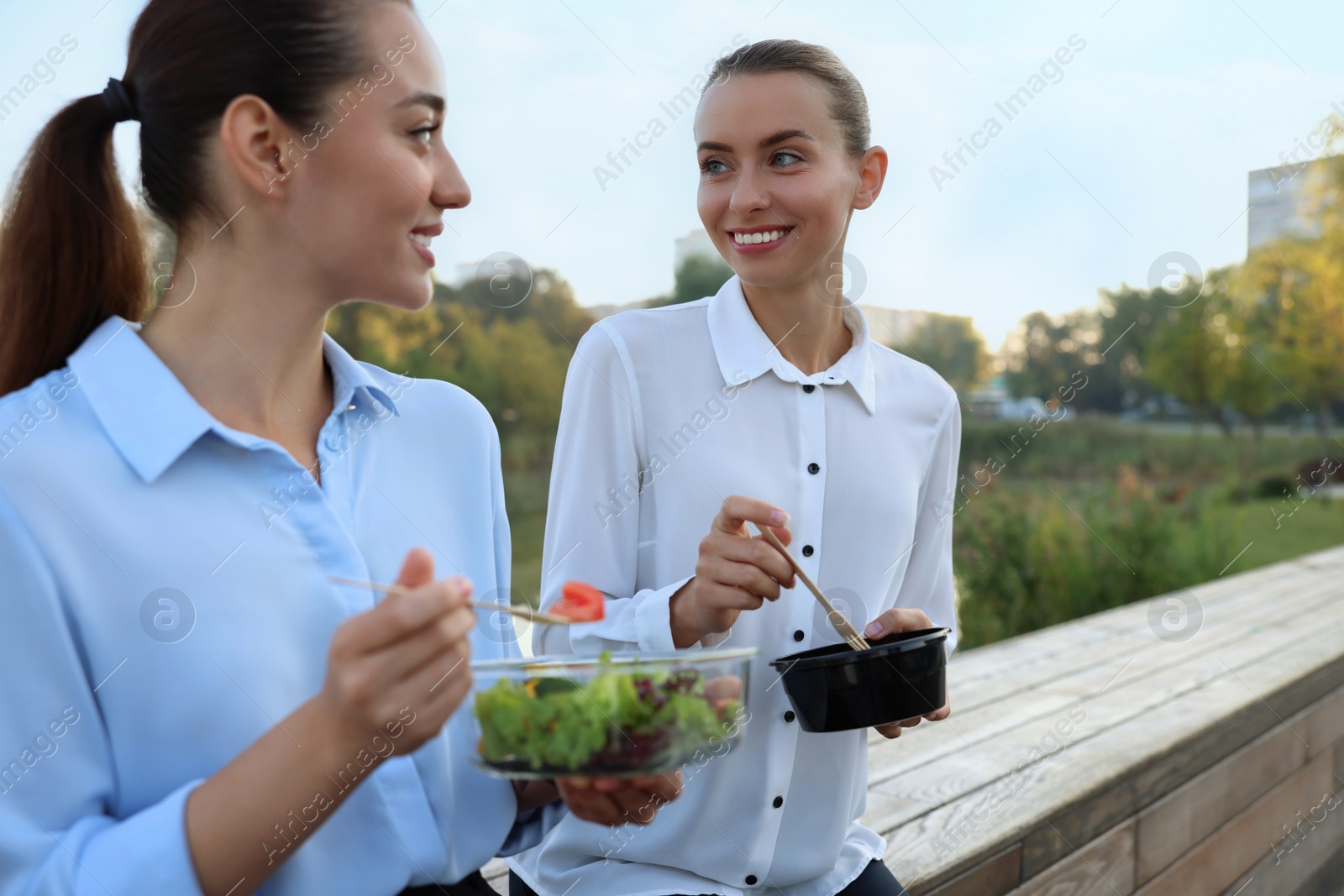 Photo of Business people eating from lunch boxes outdoors