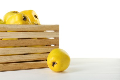 Photo of Crate with delicious fresh ripe quinces on light wooden table against white background, space for text