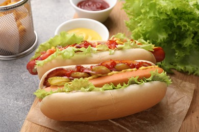 Photo of Delicious hot dogs with lettuce, onion and pickle served on grey table