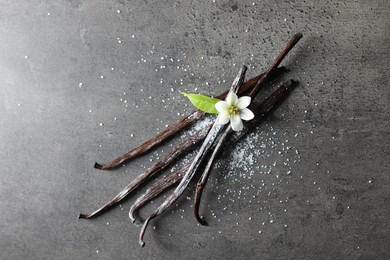 Photo of Vanilla pods, leaf and flower on grey textured table, top view