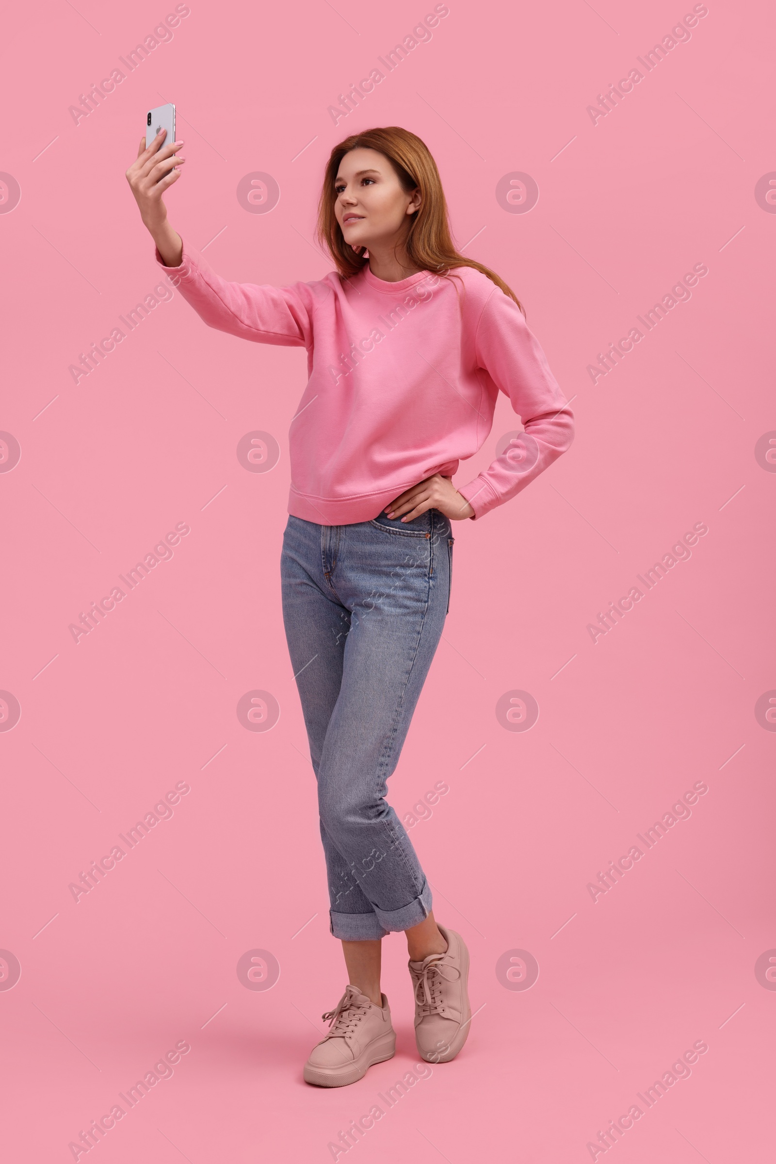 Photo of Beautiful woman taking selfie on pink background