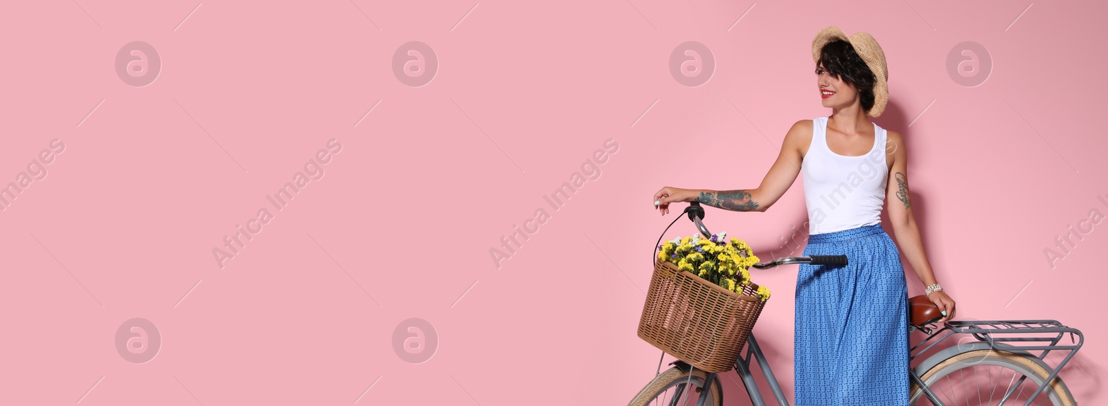 Image of Portrait of beautiful young woman with bicycle on pink background, space for text. Banner design