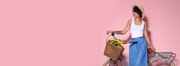 Portrait of beautiful young woman with bicycle on pink background, space for text. Banner design