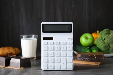 Photo of Calculator and food products on dark grey table. Weight loss concept