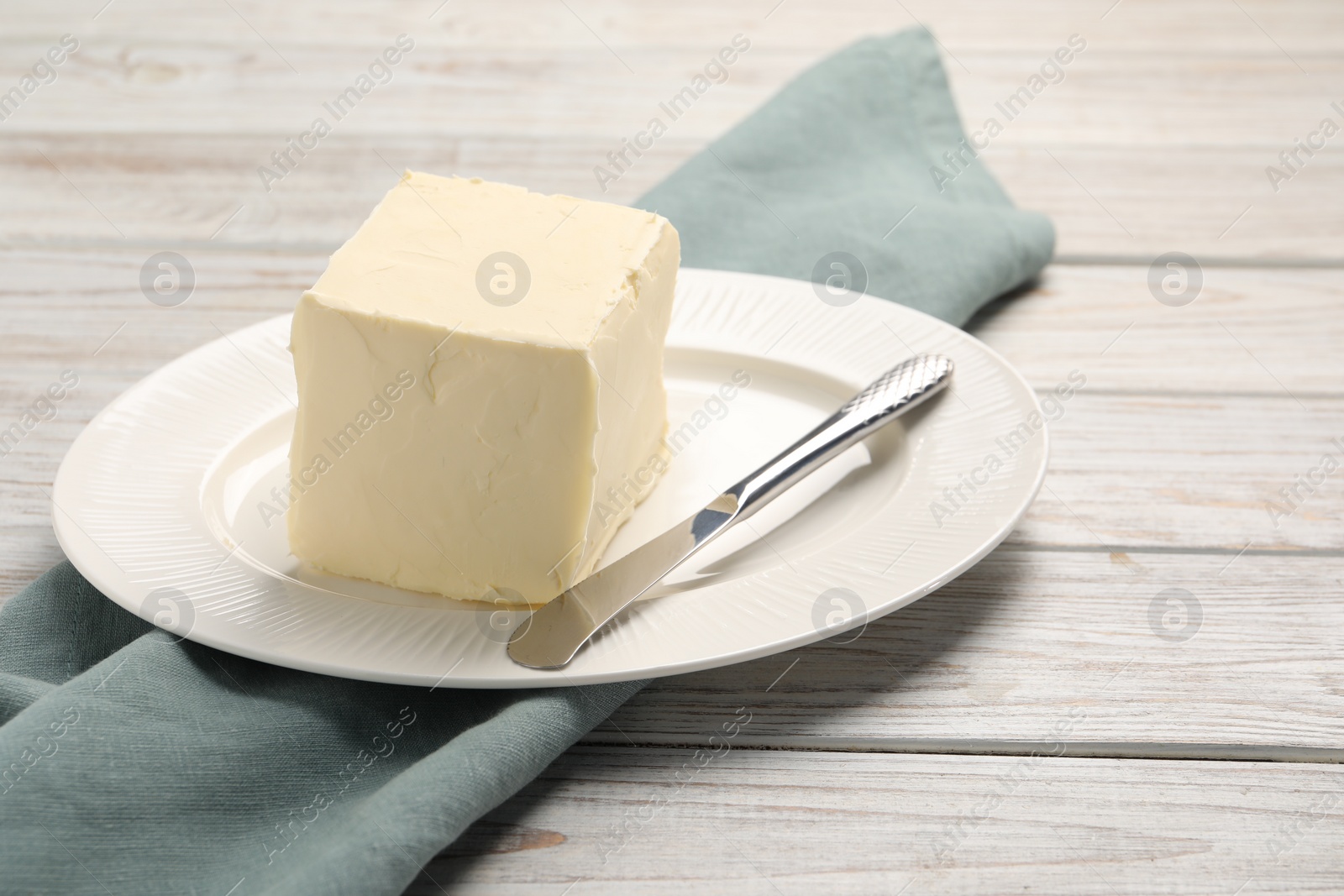 Photo of Block of tasty butter and knife on white wooden table