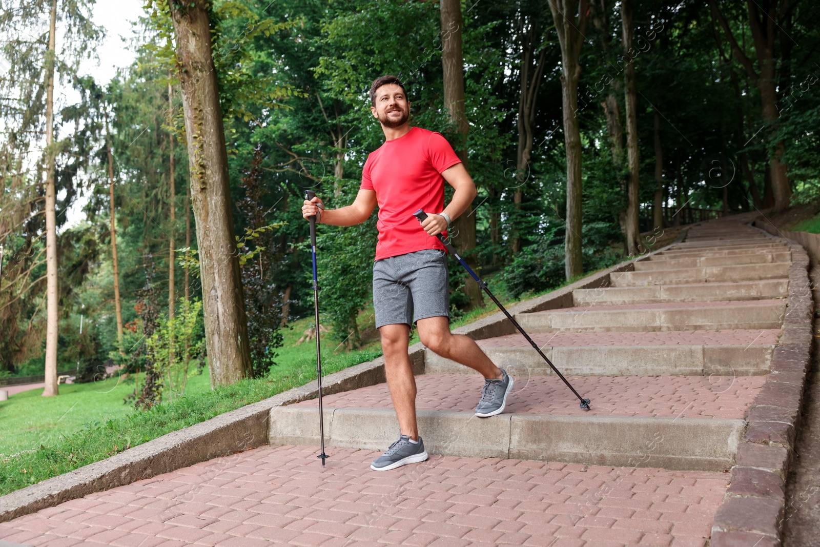 Photo of Man practicing Nordic walking with poles on steps outdoors, low angle view