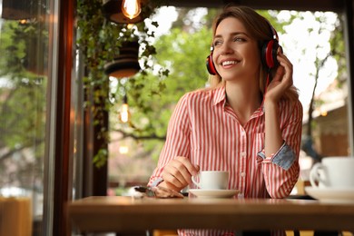 Young woman with headphones listening to music in cafe