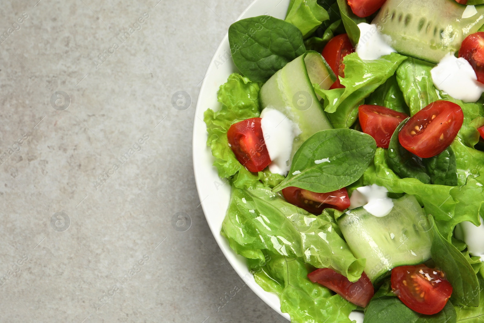 Photo of Delicious vegetable salad on light grey table, top view. Space for text