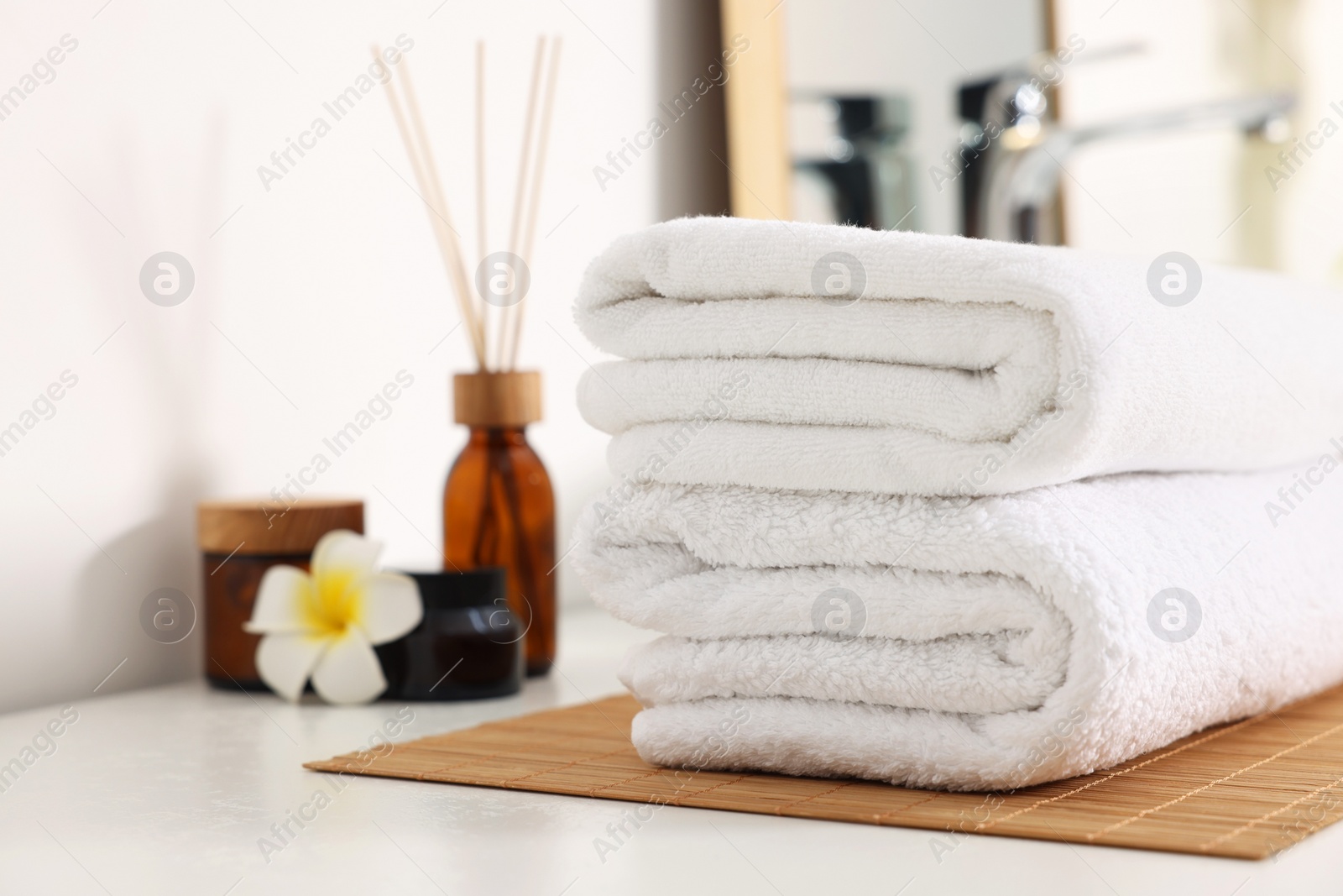 Photo of Stacked soft towels on white table in bathroom. Space for text