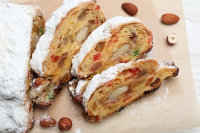 Photo of Traditional Christmas Stollen with icing sugar on parchment paper, top view