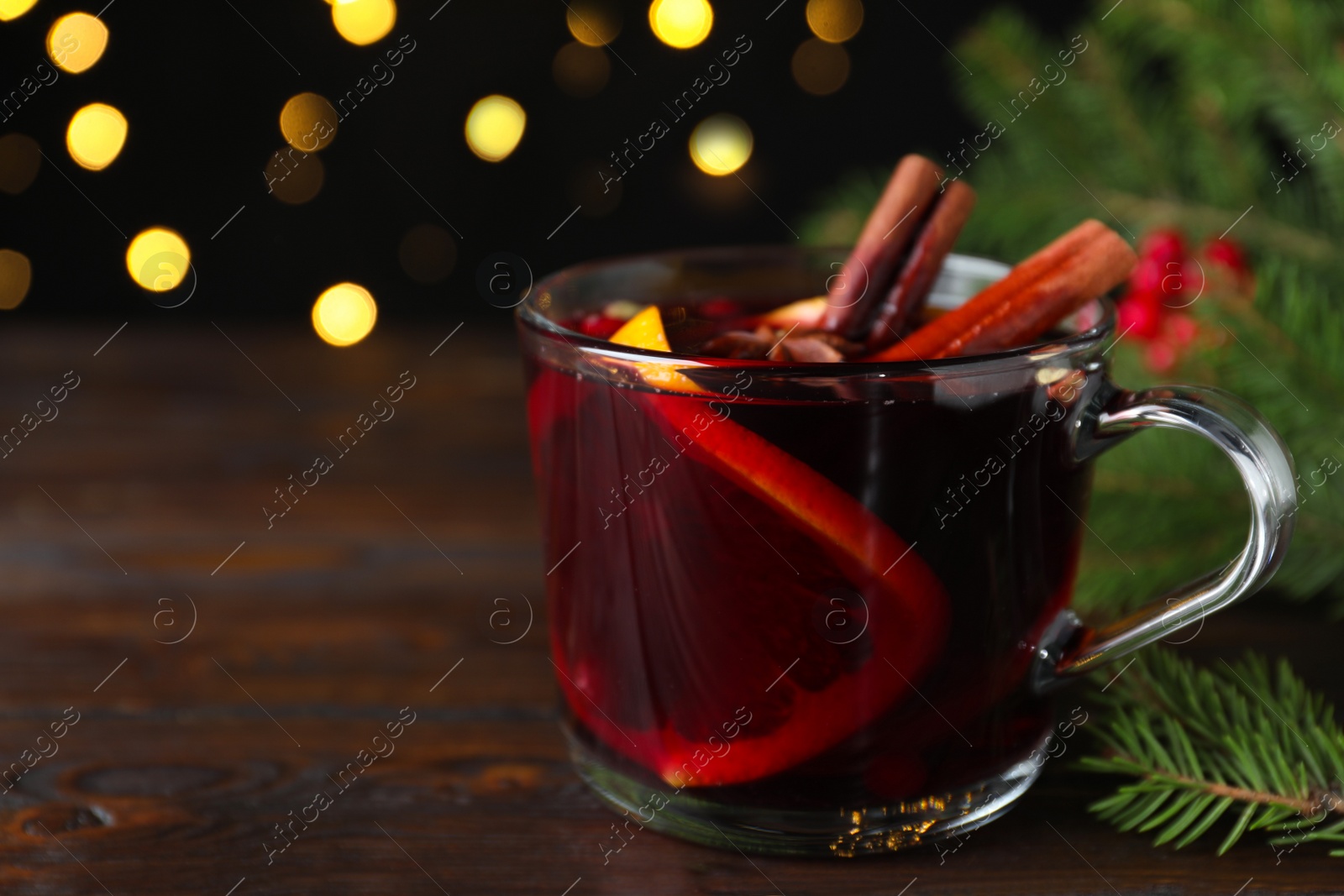 Photo of Aromatic mulled wine and fir branches on wooden table. Space for text