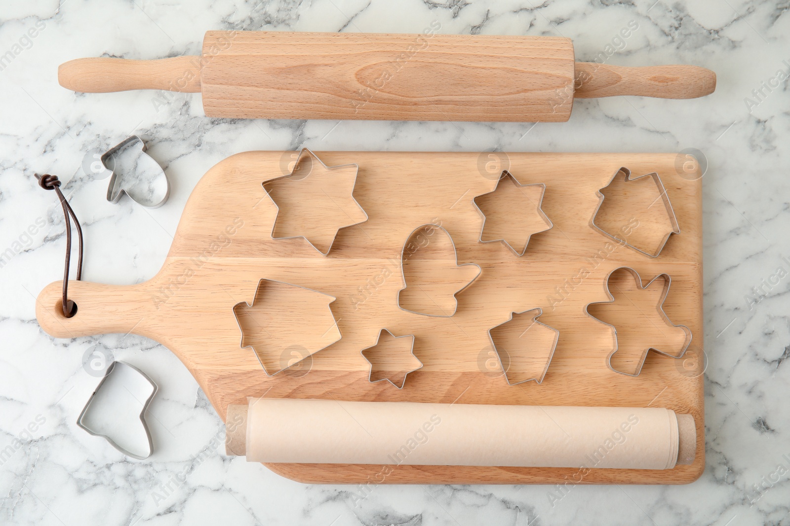 Photo of Cutters, board, rolling pin and parchment paper for homemade Christmas cookies, top view