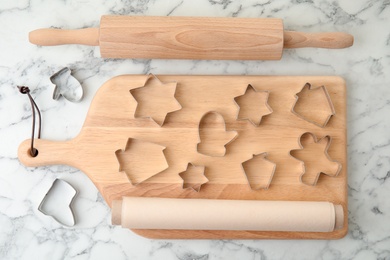 Photo of Cutters, board, rolling pin and parchment paper for homemade Christmas cookies, top view