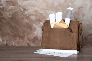 Photo of Postman's bag full of letters and newspapers on wooden background. Space for text