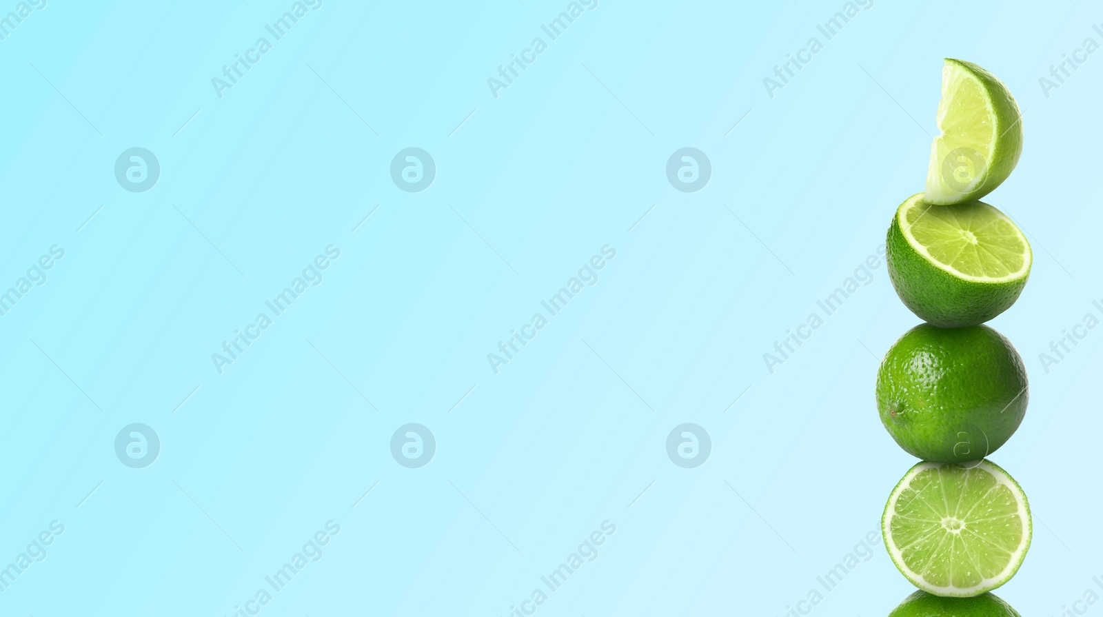 Image of Stacked whole and cut limes on light blue background, space for text