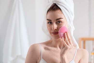 Photo of Washing face. Young woman with cleansing brush indoors, space for text