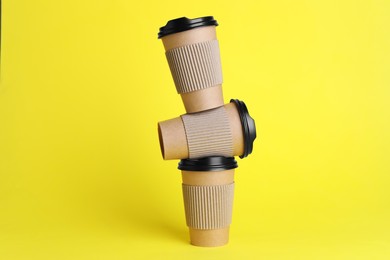 Photo of Paper cups with black lids on yellow background. Coffee to go