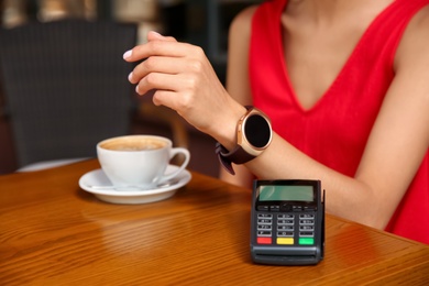 Photo of Woman making payment with smart watch in cafe, closeup