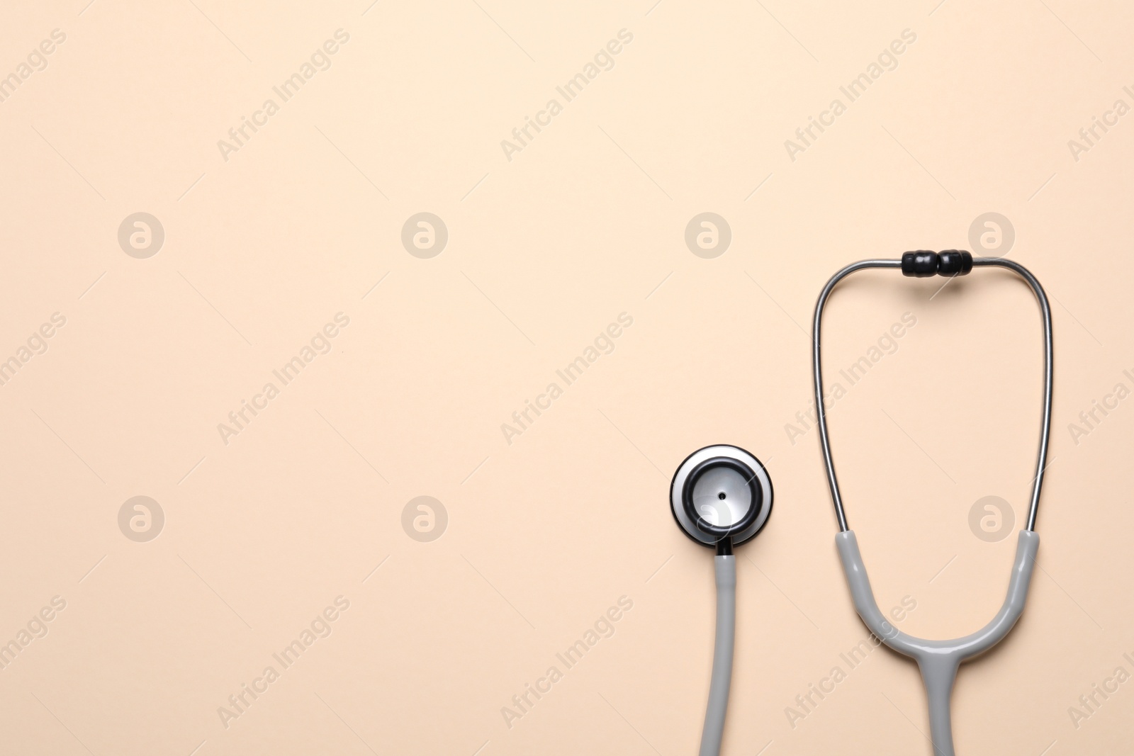 Photo of Stethoscope on beige background, top view. Space for text